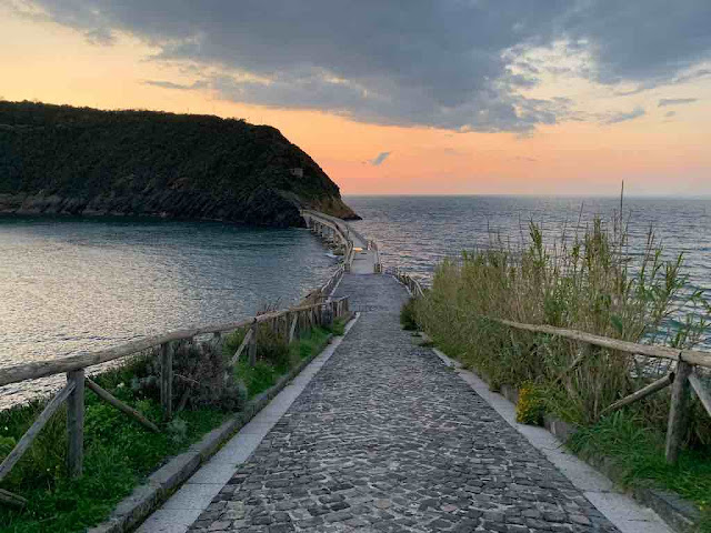 a stone pavement bridge with wooden parapets crosses the sea and connects Procida with the island of vivara